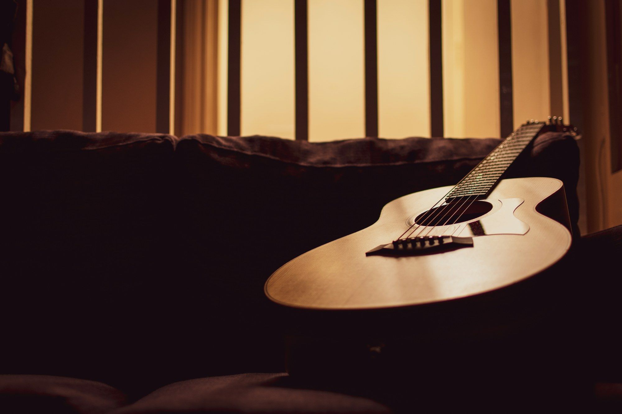 An acoustic guitar resting in low light