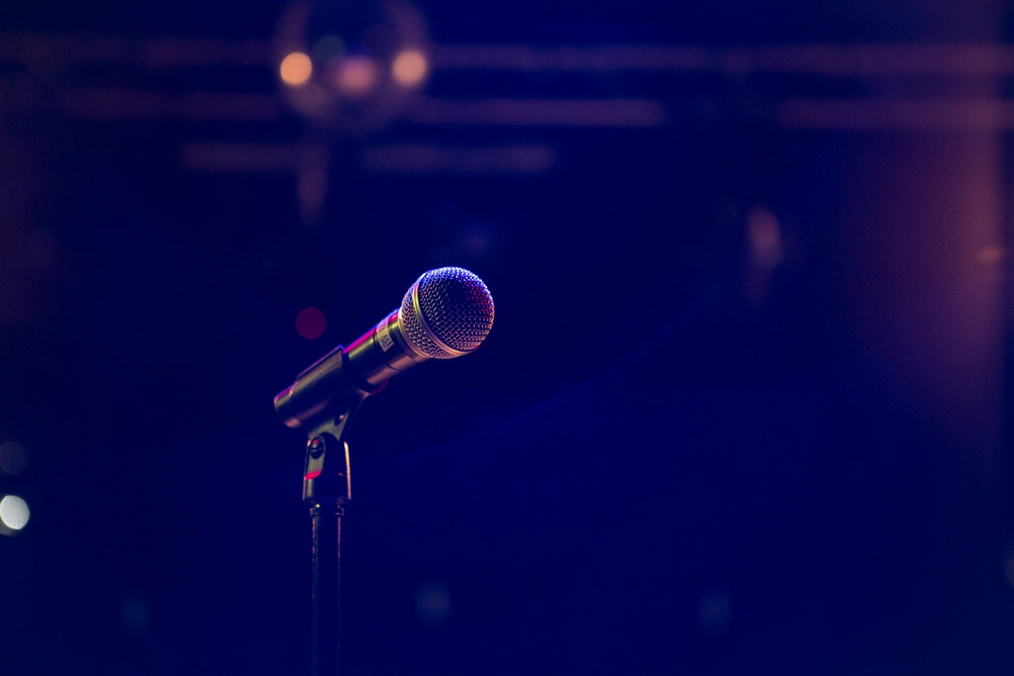 A microphone on a stand under purple stage light